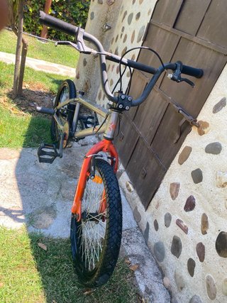 Bicicleta BMX plateada con detalles naranjas,