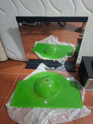 Lavabo de cristal verde con espejo.