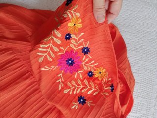 Vestido naranja con bordado floral.