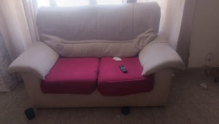 Sofá de tela beige con funda roja