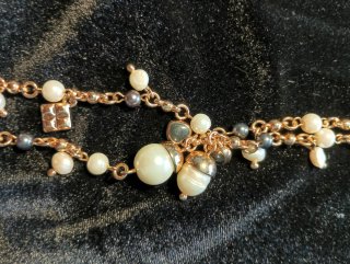 Collar de perlas blancas y negras con detalles dor