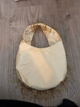 Bolso de mano dorado con flecos