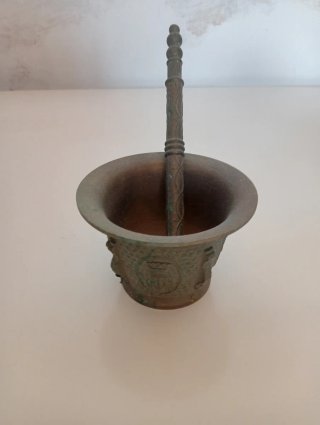 Antiguo mortero de bronce con mano