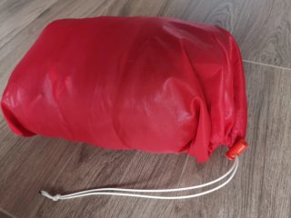 Saco de dormir azul con funda roja.