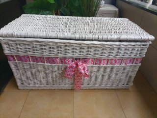 Baúl de mimbre blanco con cinta rosa.