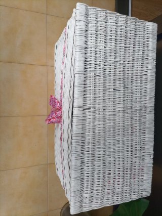 Baúl de mimbre blanco con cinta rosa.