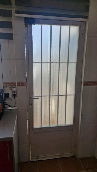 Puerta metálica con reja y cristal