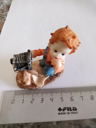 Statuina di un bambino con macchina fotografica