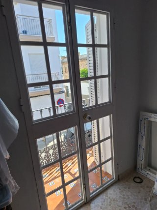 Puerta blanca con cristal y ventanas balconeras
