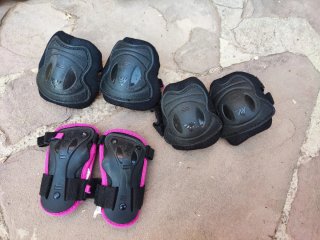 Patines en línea negros y rosas con protecciones.