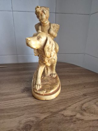 Estatuilla niño montado en perro con cesta