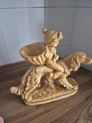 Estatuilla niño montado en perro con cesta