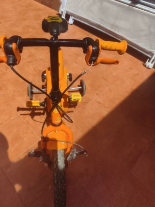 Bicicleta infantil naranja con ruedines