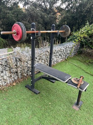 Banco de gimnasio con barra y pesas