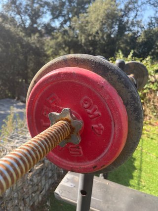 Banco de gimnasio con barra y pesas