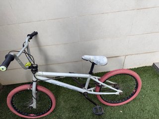 Bicicleta BMX blanca con ruedas rojas