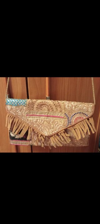 Bolso de mano dorado con flecos