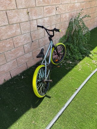 Bicicleta BMX plateada con ruedas amarillas