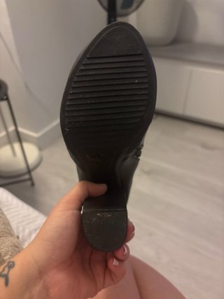 Botines de tacón negros con cremallera dorada.
