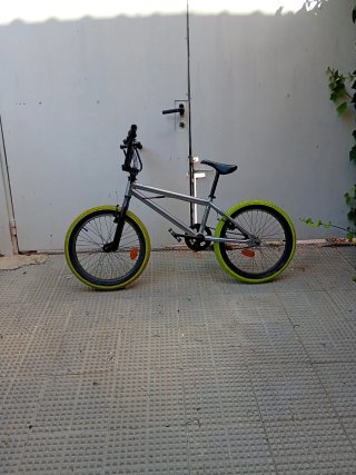 Bici BMX plateada con ruedas amarillas