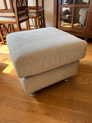 Puf de tela beige con patas metálicas