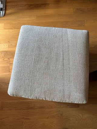 Puf de tela beige con patas metálicas