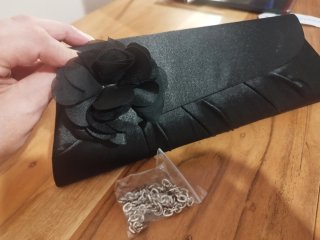 Cartera de fiesta negro con flor.