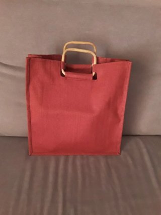 Bolsa de rafia roja con asas de bambú.