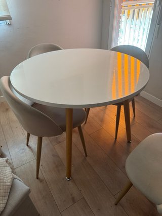 Mesa redonda blanca con patas de madera.