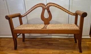 Banco de madera artesanal con cojines de cuadros.
