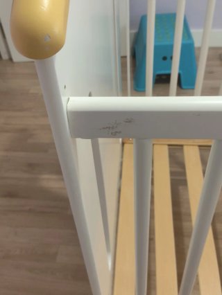 Cuna de madera blanca con letras de colores.