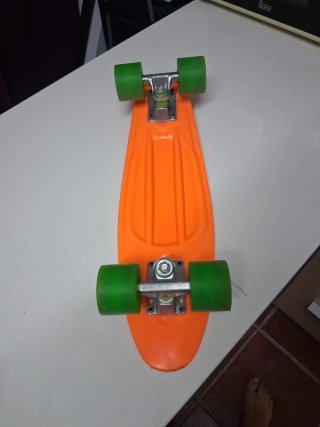 Monopatín naranja con ruedas verdes