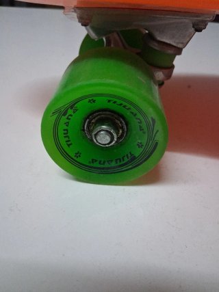 Monopatín naranja con ruedas verdes