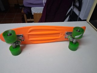 Monopatín naranja con ruedas verdes