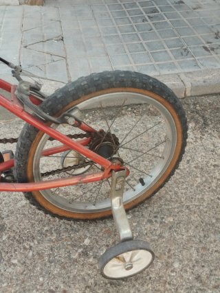 Bicicleta infantil roja con ruedines.