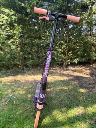 Patinete morado con ruedas naranjas