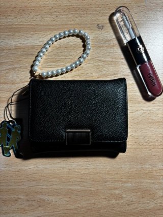 Cartera negra con pulsera de perlas