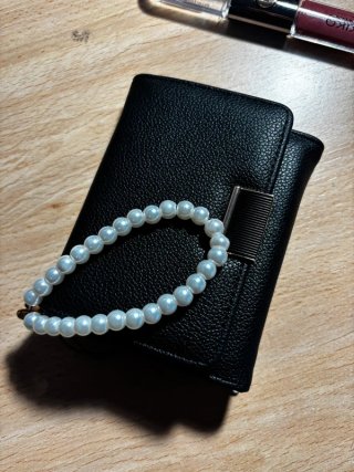 Cartera negra con pulsera de perlas