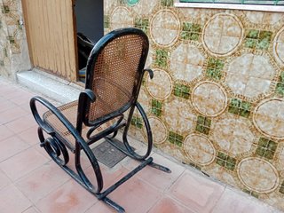 Vecchia sedia a dondolo in metallo e vimini