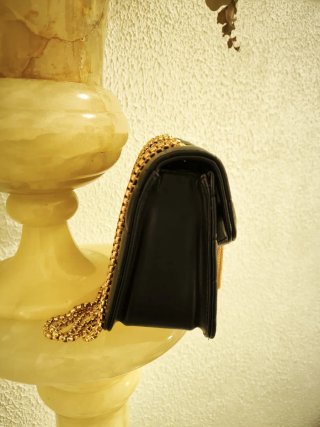 Bolso negro con inicial V y cadena dorada