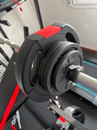 Banco de gimnasio con barra y pesas