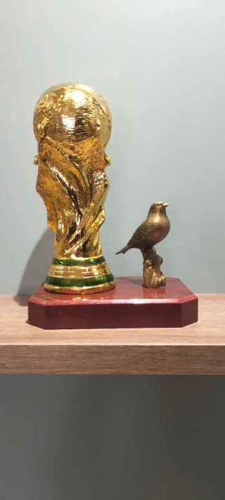Trofeo dorado con pájaro decorativo