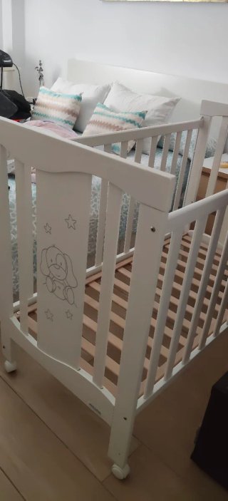 Cuna de bebé blanca con protector rosa