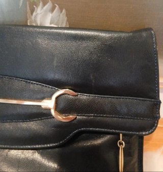 Bolso  negro con cadena y detalles metálicos.