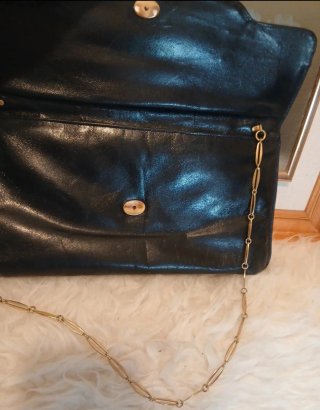 Bolso  negro con cadena y detalles metálicos.