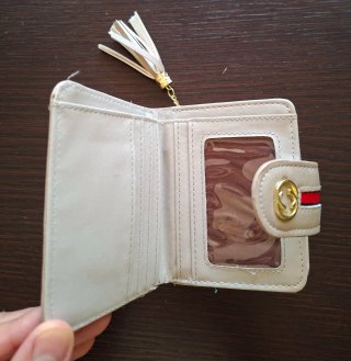 Monedero beige con detalle dorado y borla.