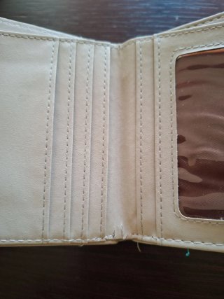 Monedero beige con detalle dorado y borla.