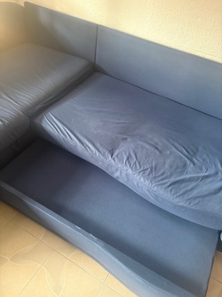 Sofá modular azul en L, con almacenaje y cama.