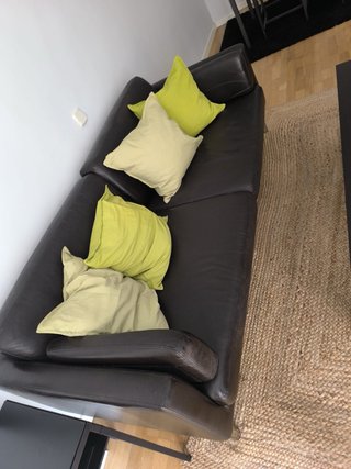 Sofá de piel marrón con cojines verdes