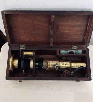 Antiguo microscopio de latón con maletín
